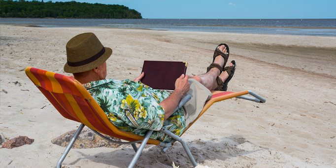 Older man sitting on the beach enjoying retirement