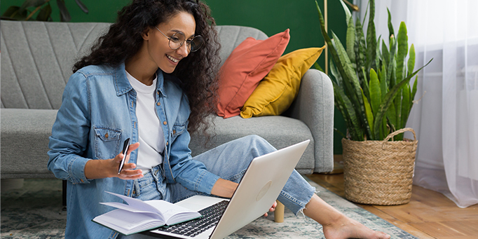 Woman sitting on floor with laptop looking at investments