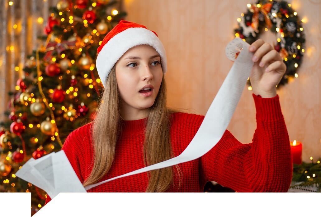 Young woman in Christmas clothing looking at a long receipt