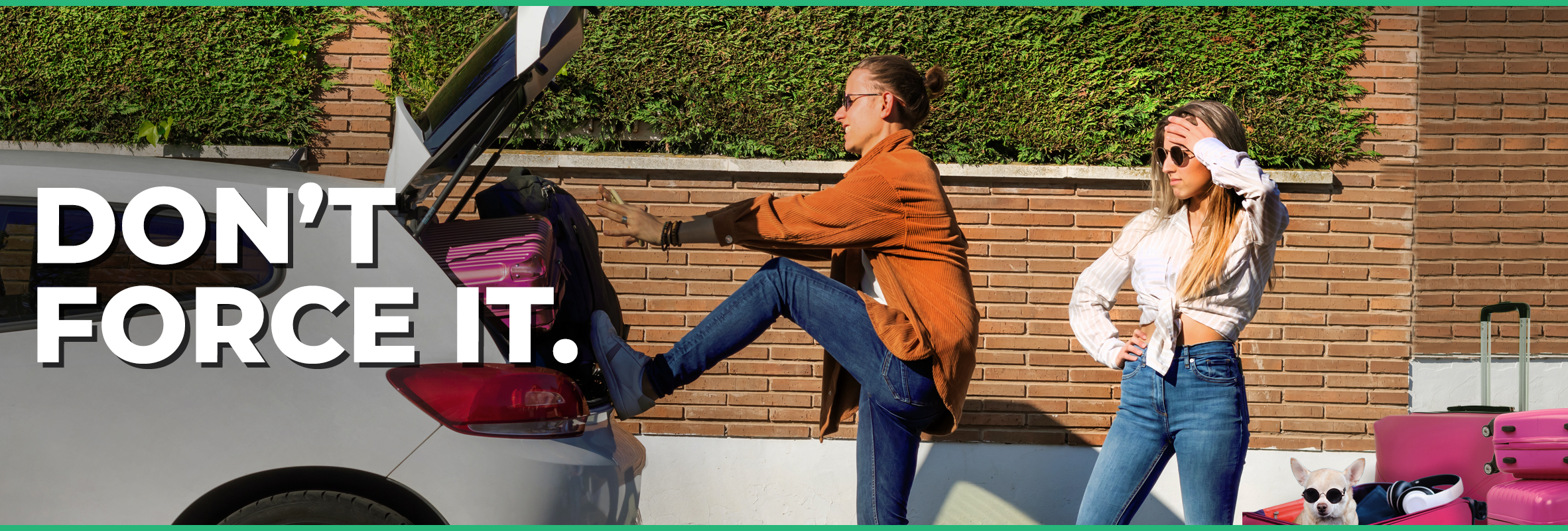 woman struggling to fit luggage into the trunk of a car while another woman watches with more luggage behind her