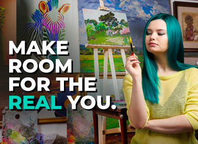 a woman with teal coloured hair stands in front of her paintings while looking at her paint brush