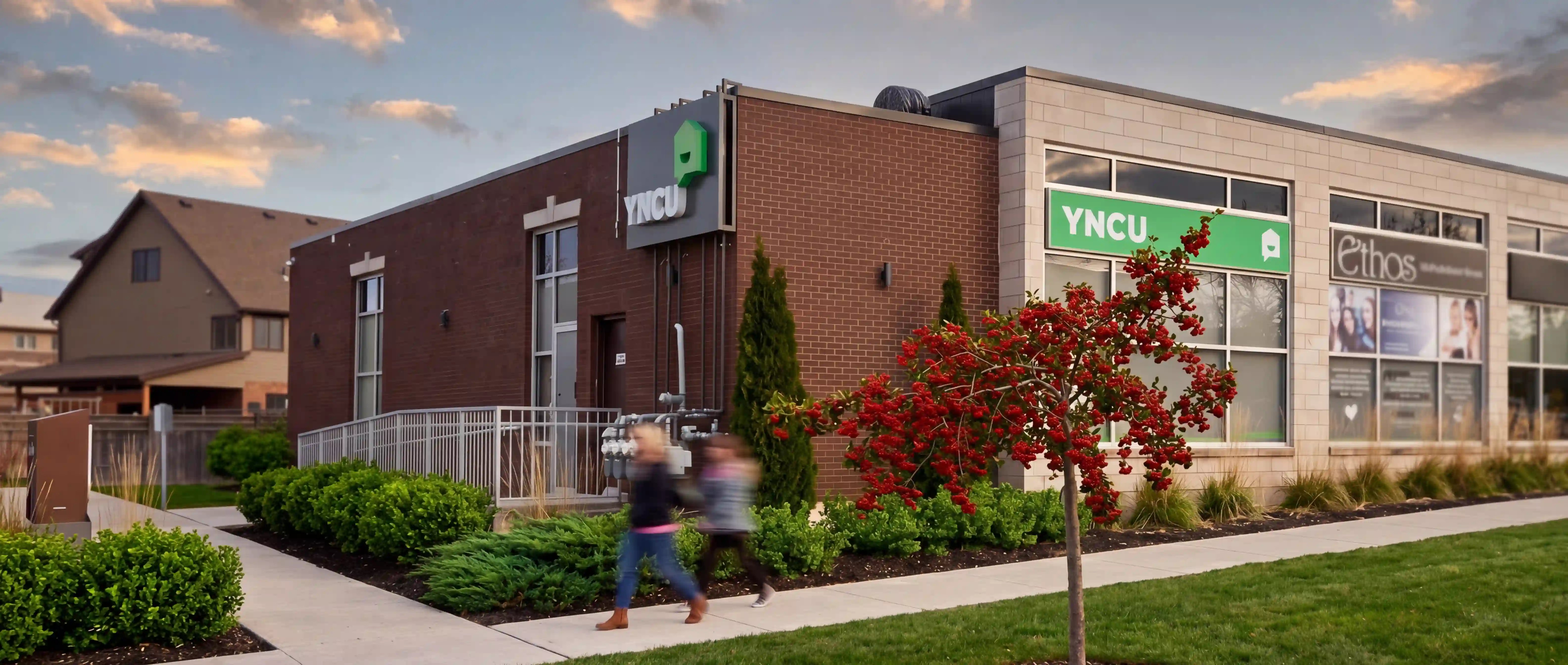An exterior photo of the YNCU London branch in the summer with 2 people walking down the street